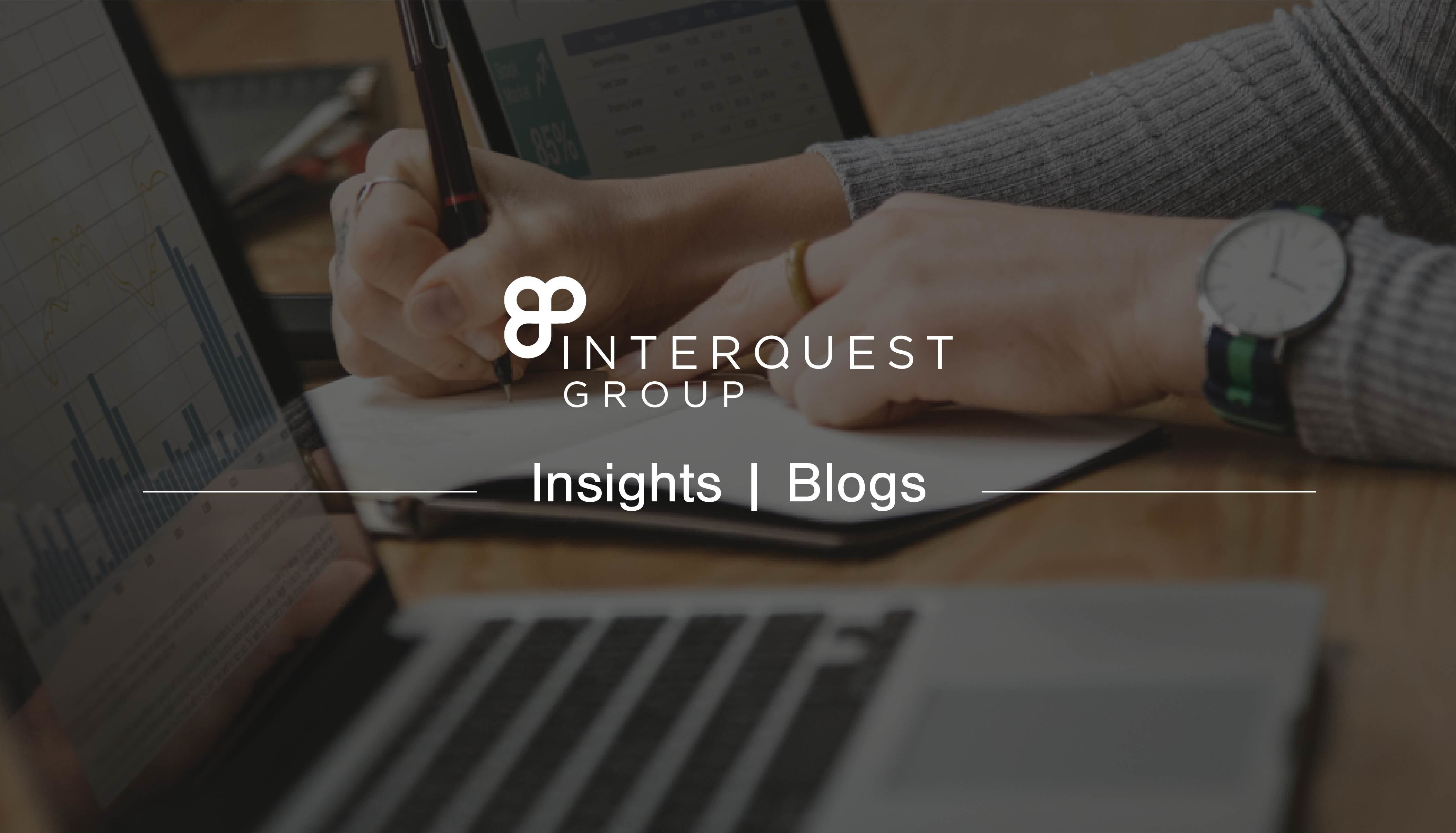 A insights banner image for a blog with the InterQuest Group logo on a image of a person writing notes from two screens