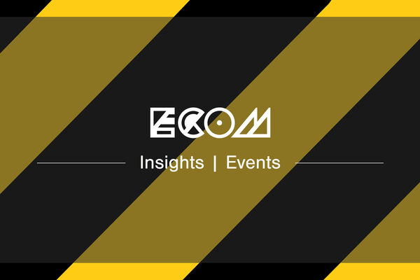 White ECOM logo insights banner on Hack Manchester black and yellow stripped background