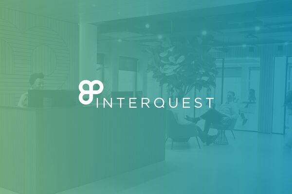 White InterQuest logo on a background image of InterQuest Group's reception area green and blue filter