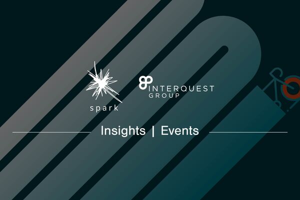 Event blog banner Spark and InterQuest Group logos in white on a graphic of a bicycle painting a route