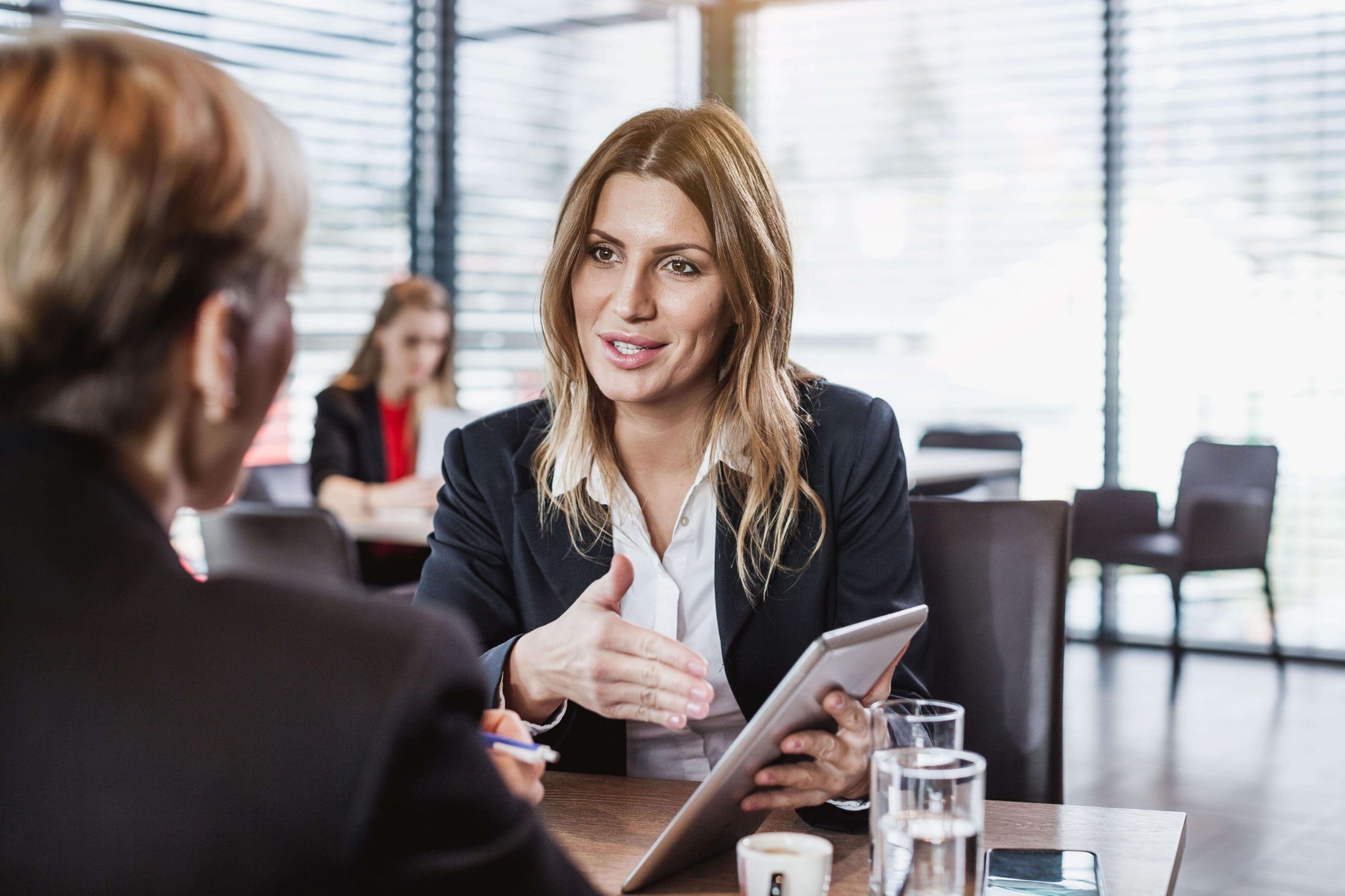 A photo of two people talking at a table using a tablet