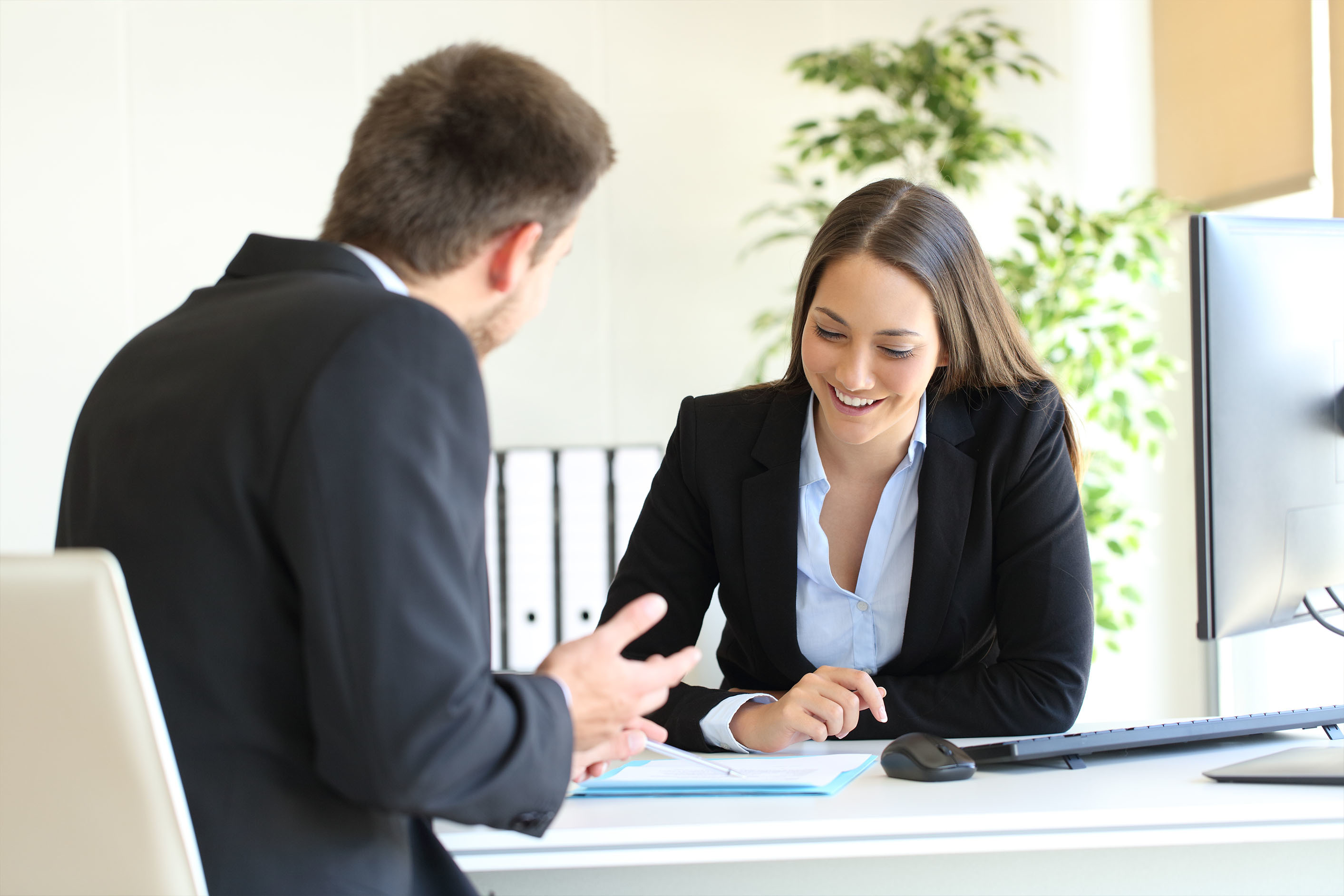 Two people sat at opposite sides of a desk looking at notes on paper