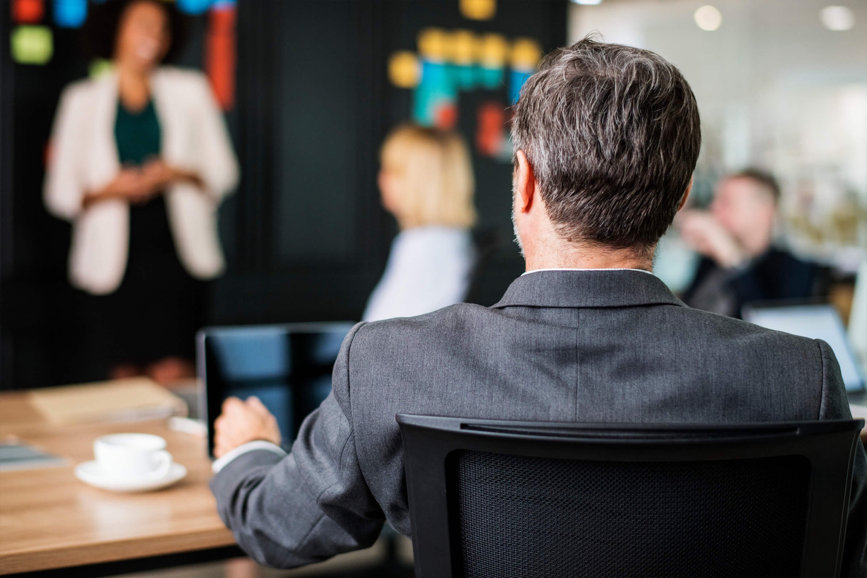 A business meeting photo of the back of a person sat in a chair