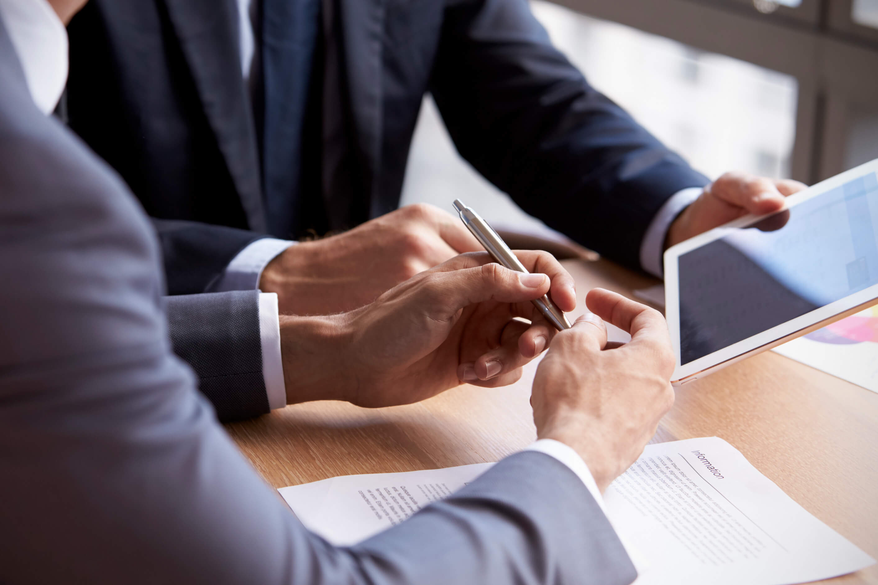 Two people in business attire sat at a table looking at a tablet screen