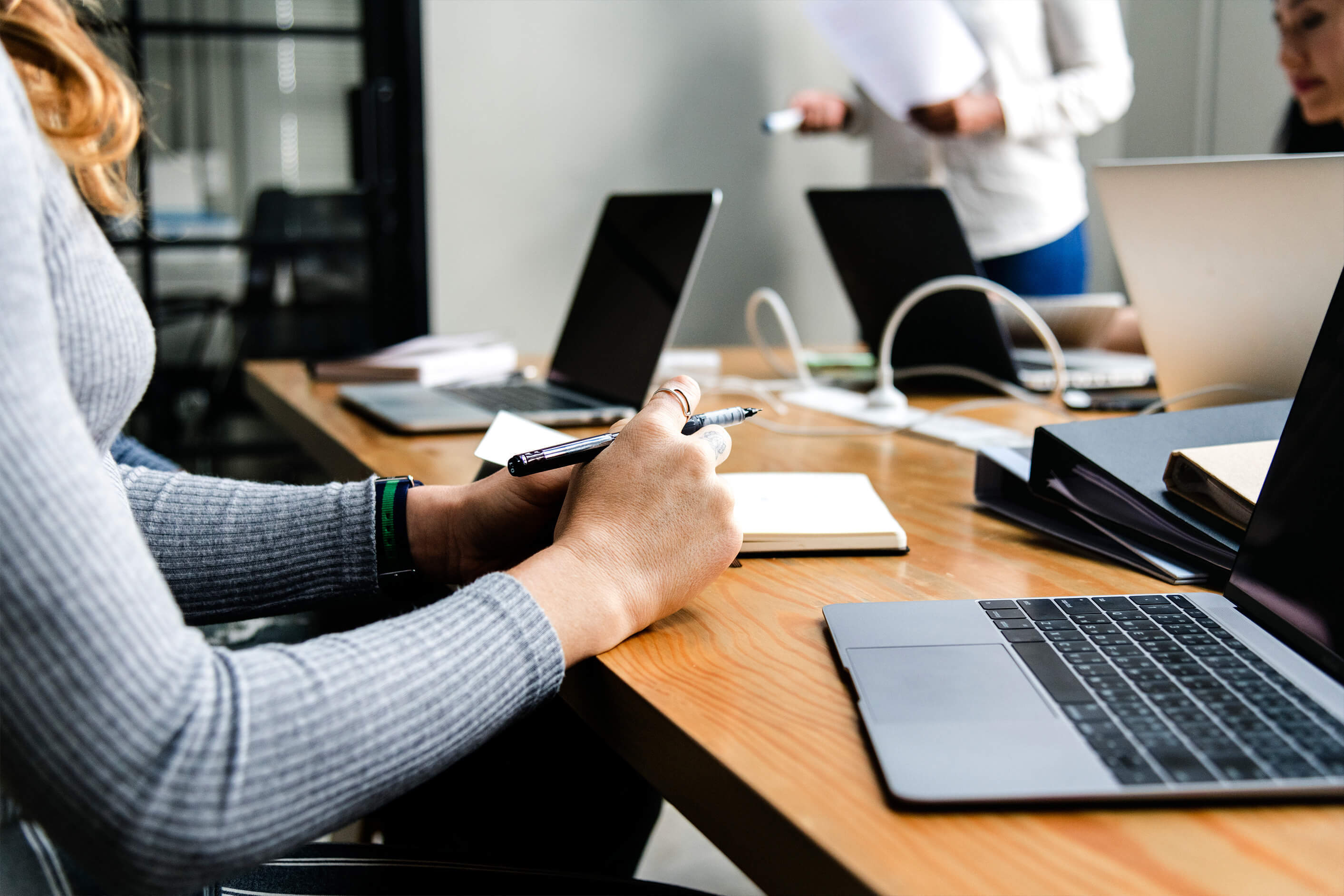 Cropped photo of people having a business meeting, laptops and folder on the desk