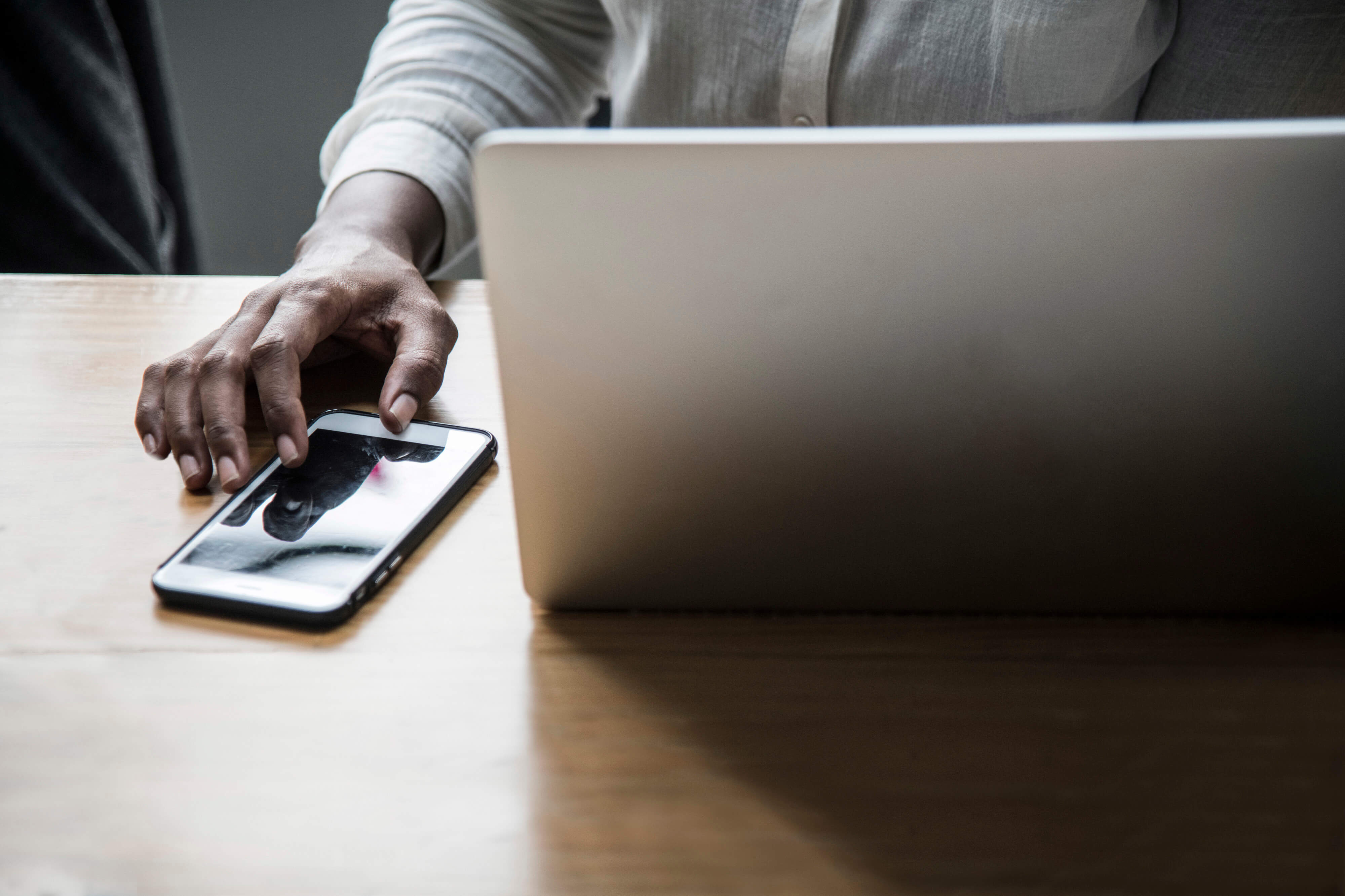 Photo of a person sat at a table with phone and laptop