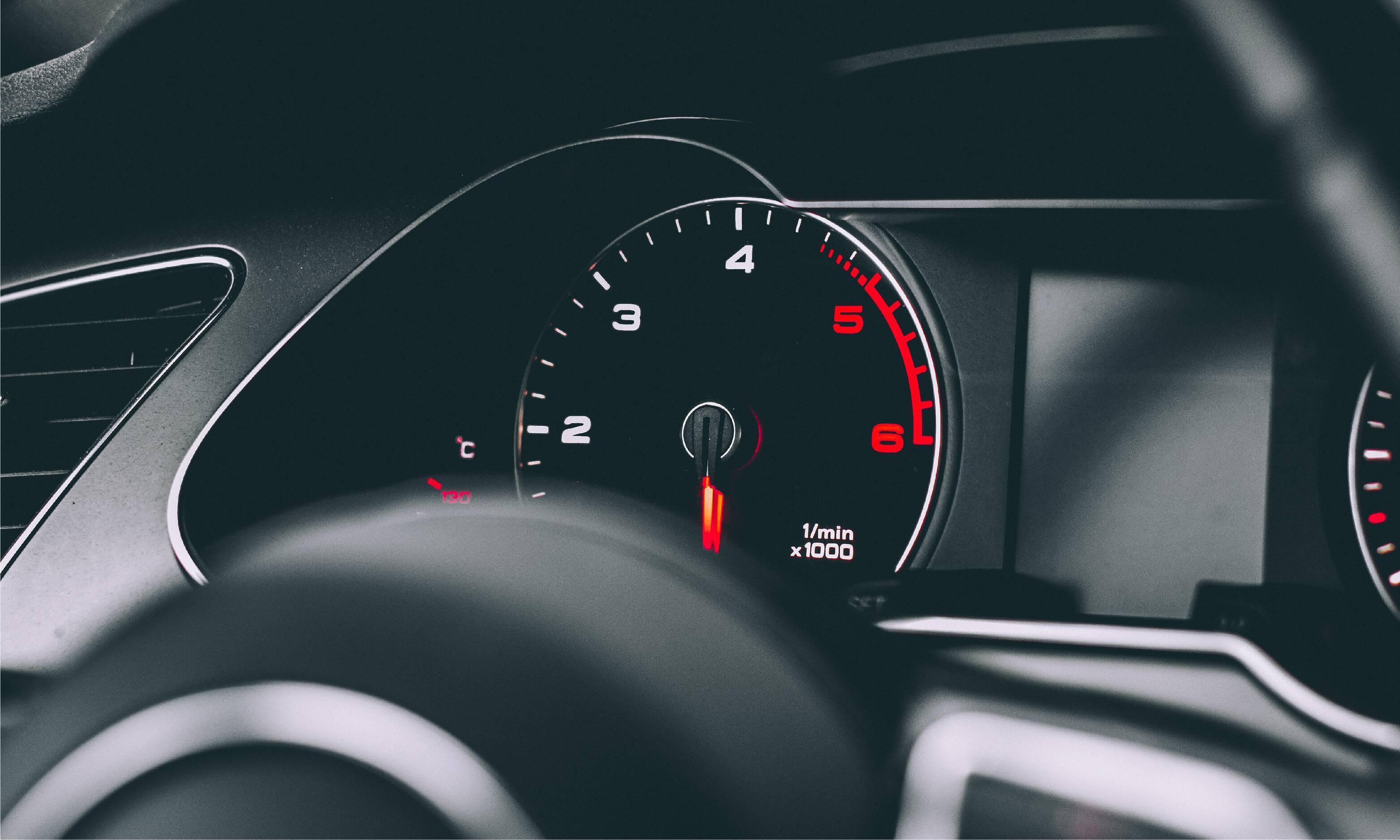 Photo of a tachometer on a car looking through the steering wheel