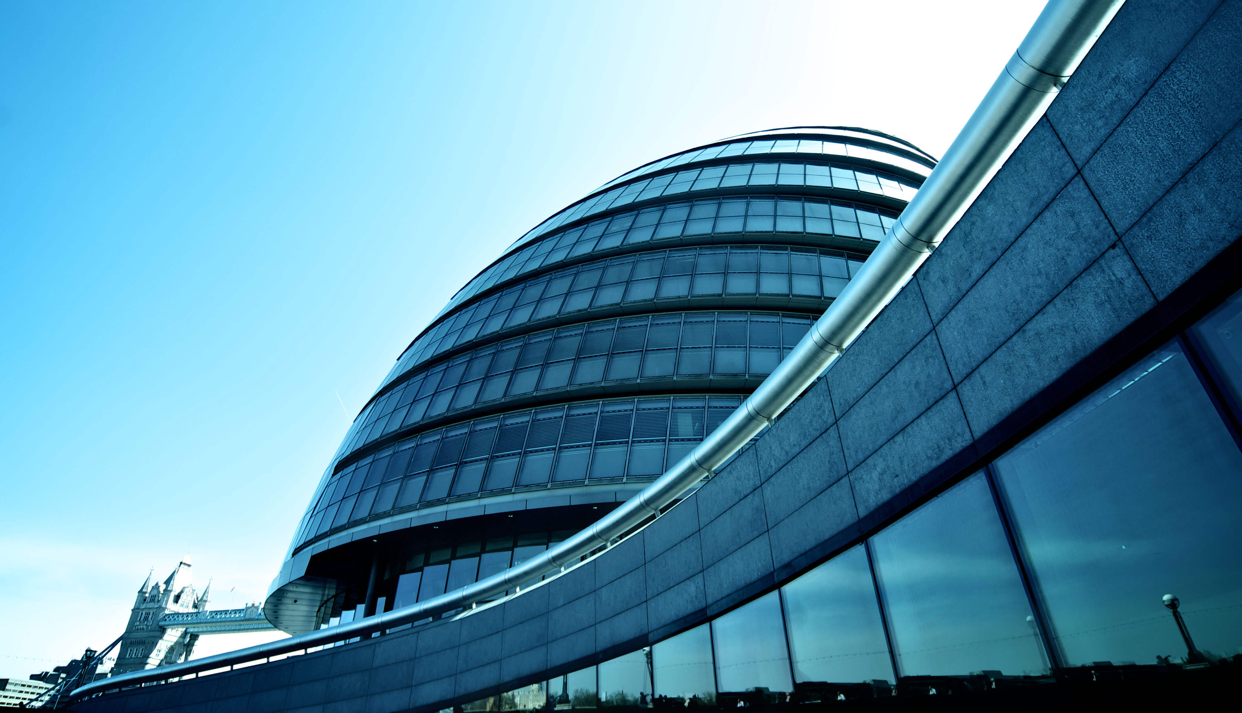 A photo taken at street-level of a dark grey building with floor-to-ceiling windows, clear blue sky