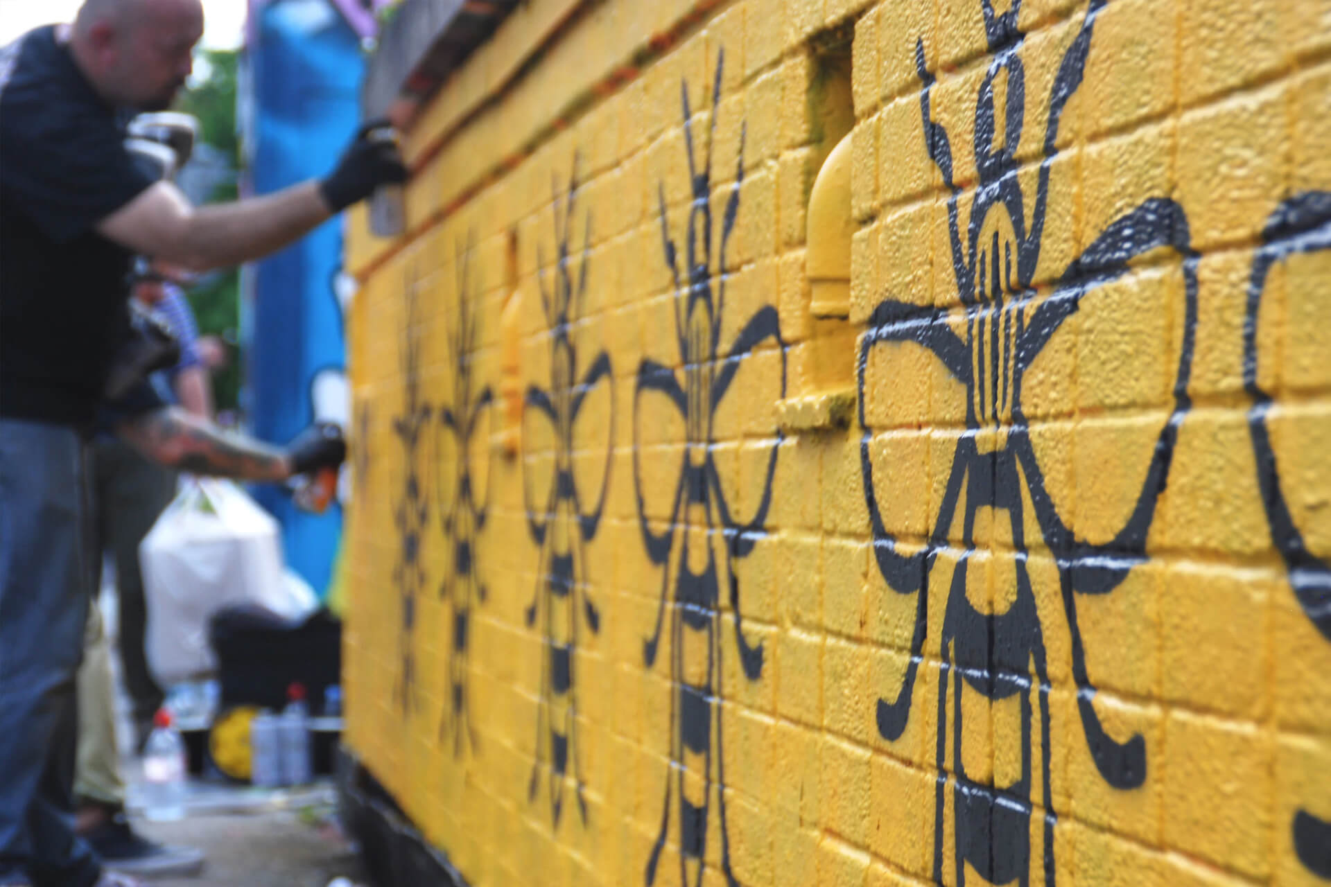 A yellow wall with the 'Manchester Bee' symbol painted on it multiple times